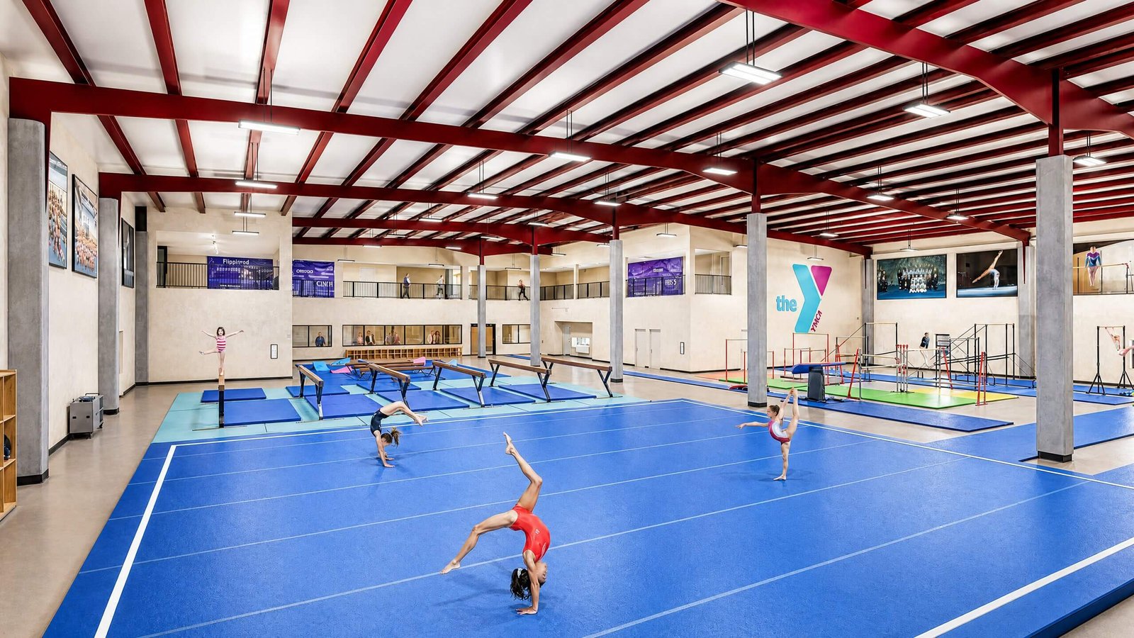 Indoor gymnastics training facility rendering with blue spring floor, balance beams, parallel bars, and high ceiling structure – sports complex visualization by Yantram Studio.